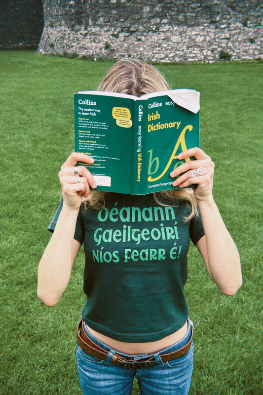 Déanann Gaeilgeoirí Níos Fearr É! - T-Léine Gaeilge (baby tee)